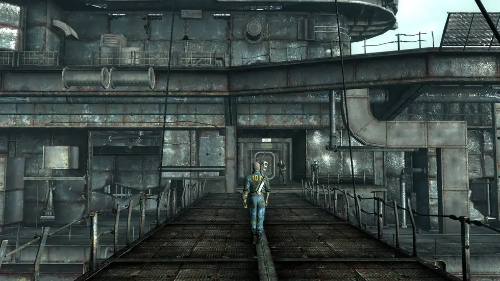 Персонаж в костюме Vault Dweller стоит на металлическом мосту заброшенной станции из игры Fallout 3