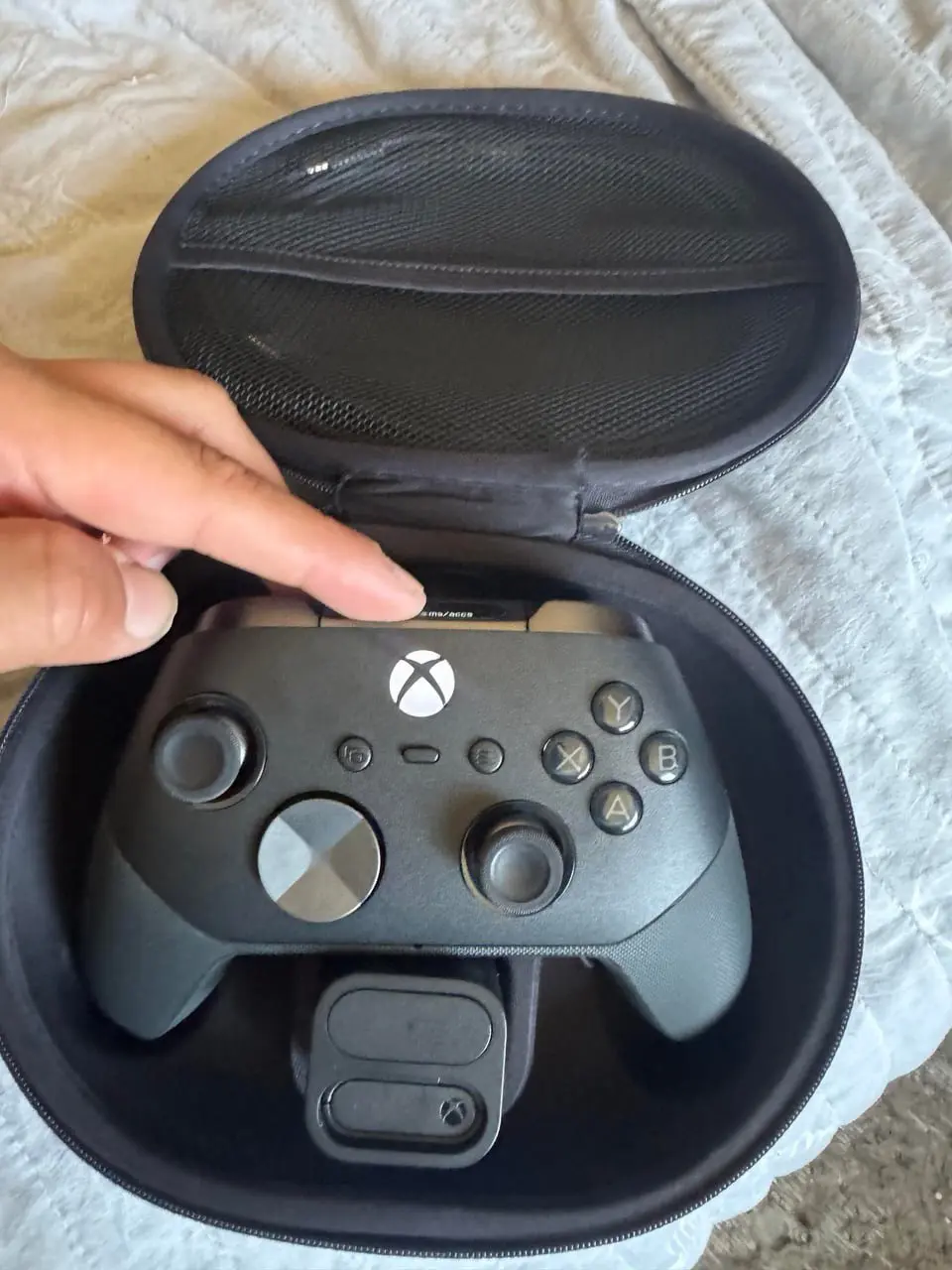 Чёрный геймпад Xbox Elite Series 2 в фирменном защитном кейсе, рука открывает крышку