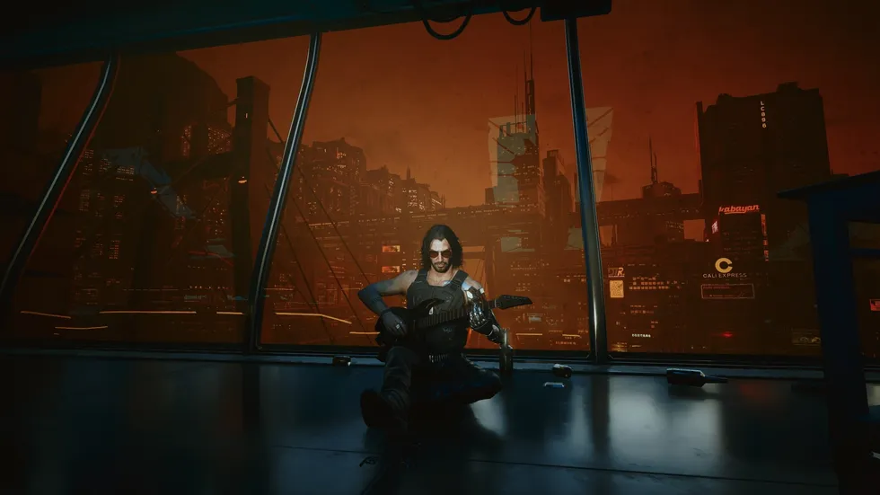 Джонни Сильверхенд из Cyberpunk 2077 играет на гитаре, сидя у панорамного окна на фоне оранжевого неба и небоскрёбов Night City